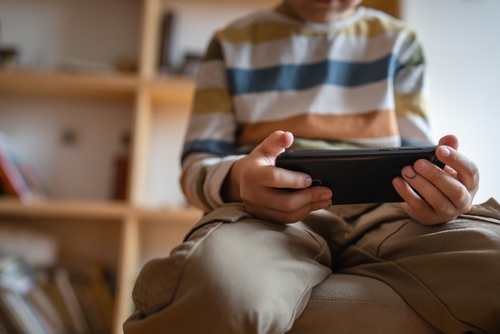 Child using smartphone at home, focused on playing a mobile game.